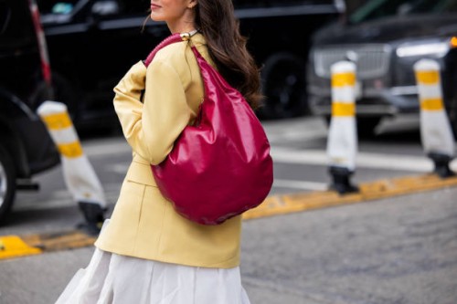 Guest wears yellow jacket, red bag, white skirt outside Altuzarra during New York Fashion Week on February 08, 2025 in New York City.