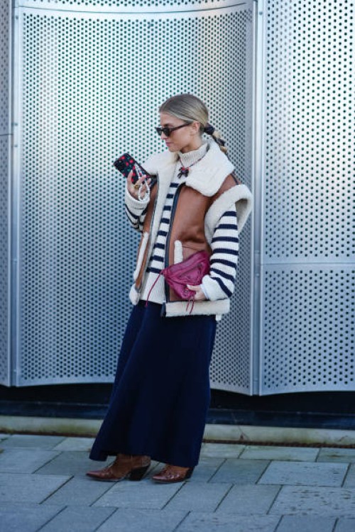 Guest wears YSL Saint Laurent sunglasses, a white ribbed wool striped black and white turtleneck pullover , a sleeveless brown leather aviator jacket...