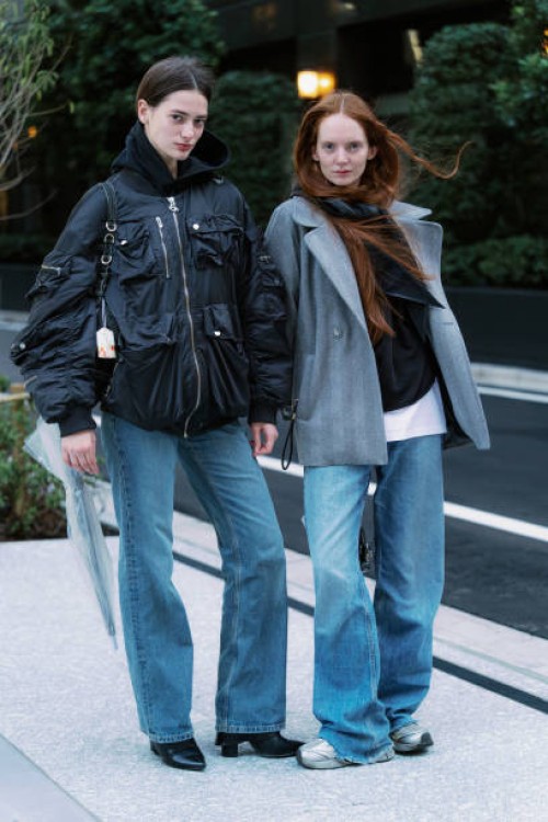 Guests are seen wearing a black hoodie, black bomber jacket, jeans, black boots; grey coat, jeans, grey sneakers during Rakuten Tokyo Fashion Week...