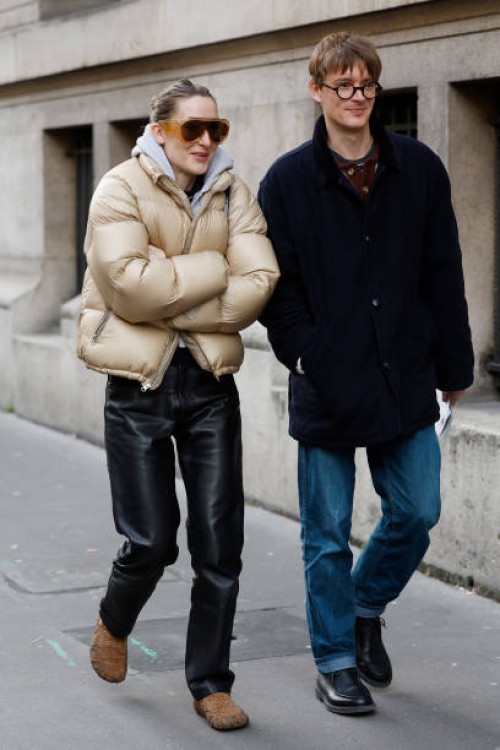 Guests wear beige bomber jacket, black leather pants, brown fur shoes, orange sunglasses , and blue jacket, blue jeans, black shoes , outside Issey...