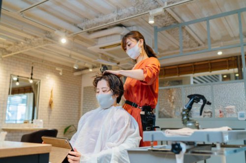hair dresser drying costumer's hair. owner and customer wearing protective face mask for illness prevention - hairstyle stock pictures, royalty-free photos & images