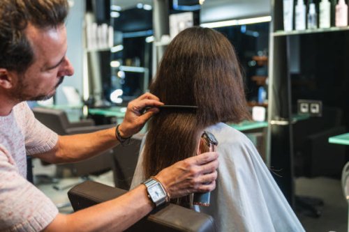 hairdresser holding clippers, cutting long hair for a bold new look at a modern salon. - hairstyle stock pictures, royalty-free photos & images