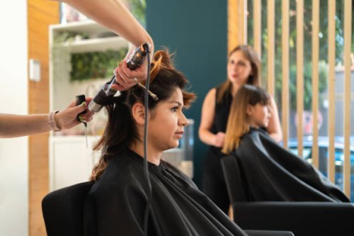 hairdresser using an electric curling iron with a client - hairstyle stock pictures, royalty-free photos & images
