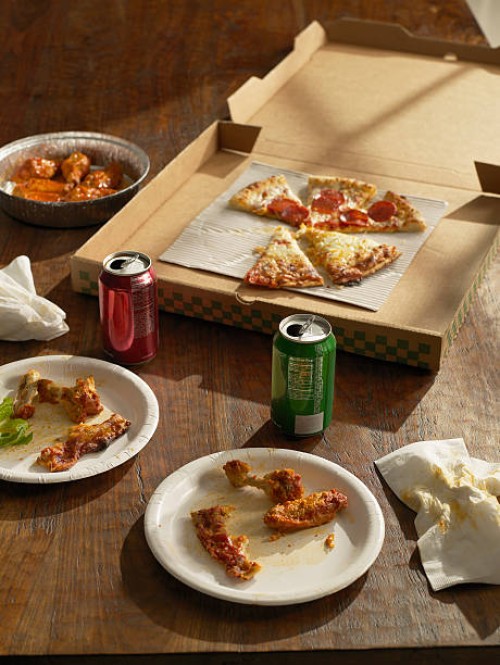 half-eaten pizza , buffalo wings and sodas - junk food stockfoto's en -beelden
