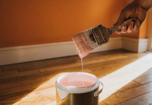 hand dipping a paint brush into a large tin of pink paint as it drips back into the pot - home decoration stock pictures, royalty-free photos & images