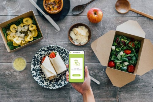 hand holding smartphone, vegetarian takeaway food on dining table - junk food stock pictures, royalty-free photos & images