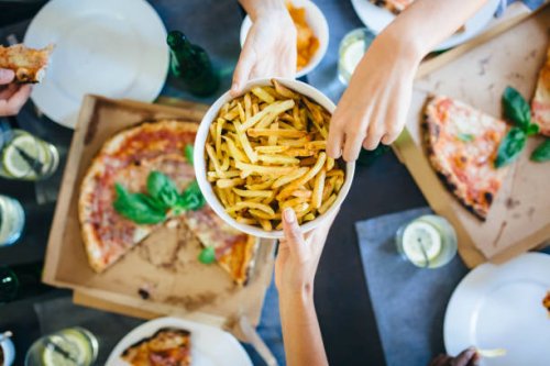 hand taking french fries from bowl - junk food stock pictures, royalty-free photos & images