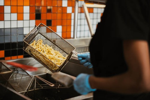hands, fries and fast food kitchen worker at fryer with gloves, cooking and order process at small business. restaurant chain, working and cook preparing chips for lunch service with hospitality. - junk food stock pictures, r