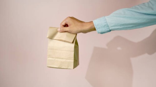 hands holding food delivery paper bag with pink background - junk food stock pictures, royalty-free photos & images
