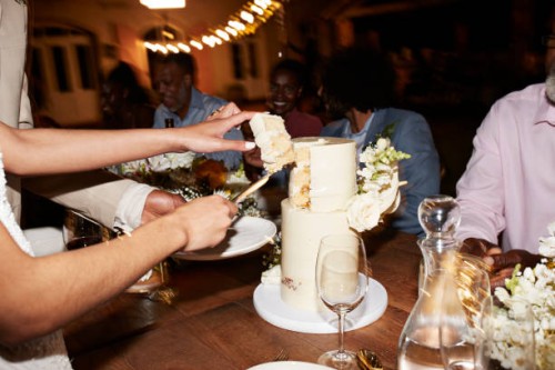 hands of newlywed couple cutting wedding cake near guests - home decoration stock-fotos und bilder