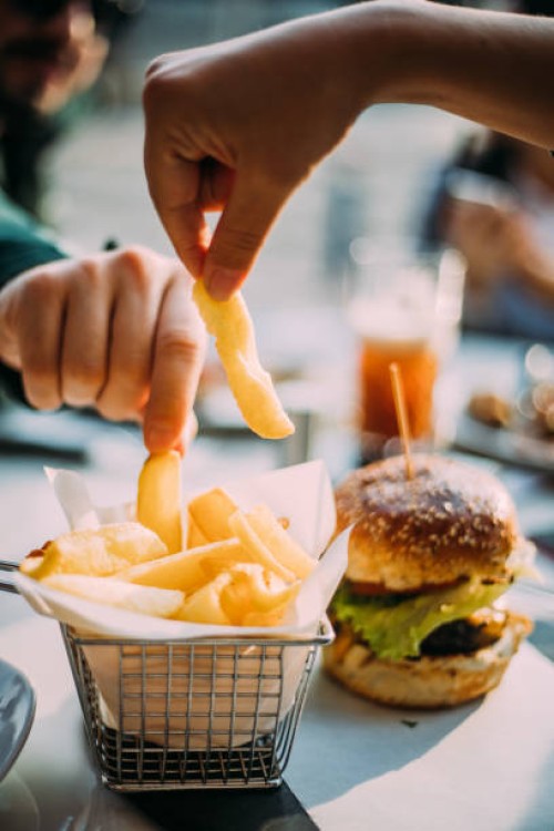 hands of two young people sharing bowl of french fries - food stock pictures, royalty-free photos & images