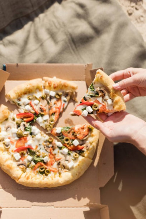 hands of woman holding pizza slice on sunny day - junk food stock pictures, royalty-free photos & images