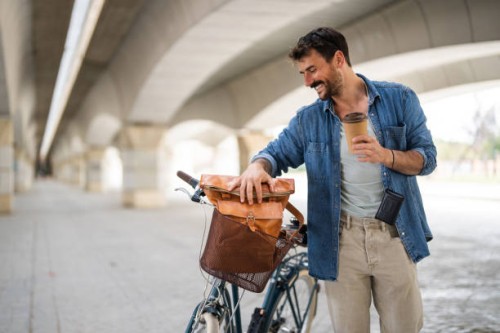 handsome young man with bicycle in a city and takeaway cup of coffee - junk food stock pictures, royalty-free photos & images