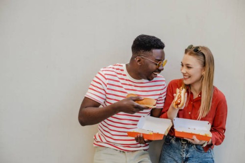 hanging out and eating hot dog with a friend outdoors - junk food stock pictures, royalty-free photos & images