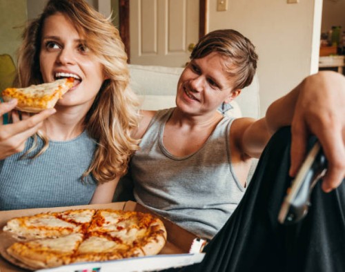 happiness couple eating a pizza at home - junk food stock pictures, royalty-free photos & images