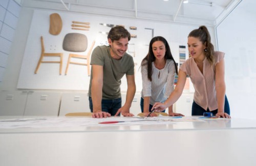 happy architect talking to her clients at the office and showing them a design for their house - home decoration stock pictures, royalty-free photos & images