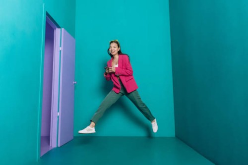 happy asian woman jumping in color room holding smartphone - fashion stock pictures, royalty-free photos & images