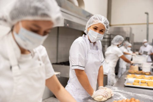 happy baker working at a food processing plant kneading the dough - food stock pictures, royalty-free photos & images