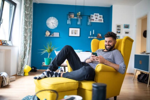 happy bearded man sitting on armchair and using smart phone - home decoration stock pictures, royalty-free photos & images