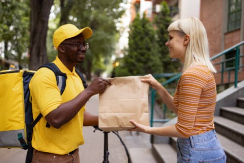 happy black courier handing over a delivery to his female customer. - junk food stock pictures, royalty-free photos & images