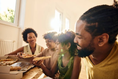 happy black family eating pizza in their new home. - junk food stock pictures, royalty-free photos & images