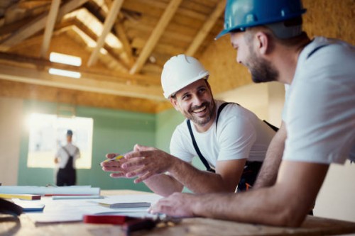 happy construction workers talking about plans while working in a house. - home decoration stockfoto's en -beelden