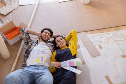 happy couple day dreaming with color swatches lying on floor in new living room - home decoration stock pictures, royalty-free photos & images
