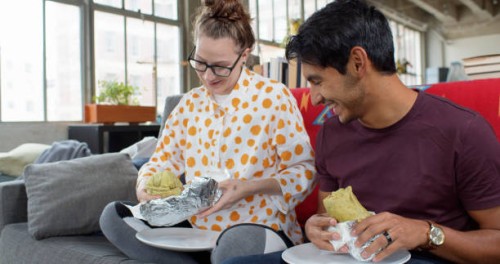 happy couple eating burritos at home - junk food stock pictures, royalty-free photos & images