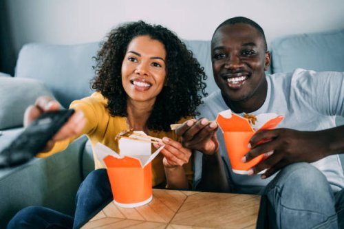 happy couple eating chinese food and watching tv at home. - junk food stock pictures, royalty-free photos & images