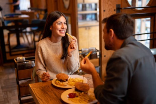happy couple eating in the restaurant - junk food stock pictures, royalty-free photos & images