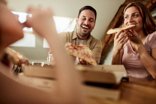 happy couple eating pizza for lunch at home. - junk food stock pictures, royalty-free photos & images