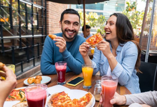 happy couple eating pizza with a group of friends - food stock pictures, royalty-free photos & images