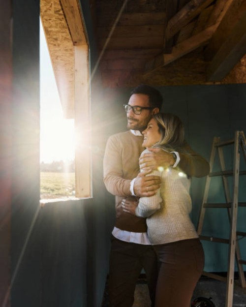 happy couple embracing by the window frame at construction site. - home decoration stock pictures, royalty-free photos & images