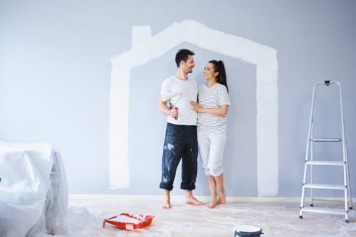 happy couple painting in new apartment with house shape on wall - home decoration stockfoto's en -beelden