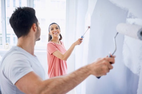 happy couple painting wall in apartment together - home decoration stock pictures, royalty-free photos & images