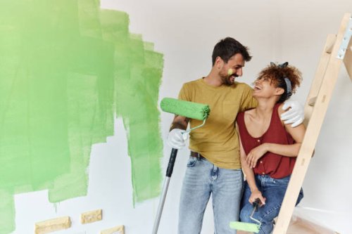 happy couple talking while painting their new apartment. - home decoration stock pictures, royalty-free photos & images