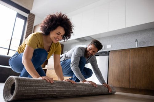 happy couple unrolling a carpet at home - home decoration stock pictures, royalty-free photos & images