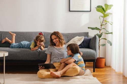 happy family moments: the mother sits on the floor and watches something on the digital tablet with her kids - home decoration stock pictures, royalty-free photos & images