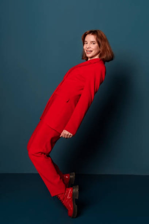 happy fashionable woman posing standing in red pantsuit studio shot on blue background indoors - fashion stock pictures, royalty-free photos & images