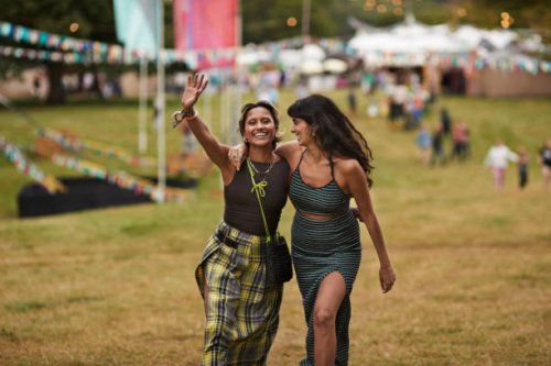 happy female friends walking with arms around at park - concert stock pictures, royalty-free photos & images