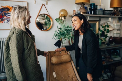 happy female owner talking with customer buying furniture at antique store - home decoration stock pictures, royalty-free photos & images