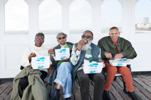 happy male and female friends having fish and chips - junk food stock pictures, royalty-free photos & images