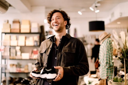 happy male customer looking away while buying shoe at retail store - fashion stock pictures, royalty-free photos & images