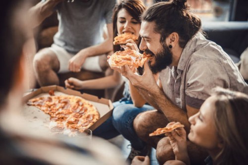 happy man eating pizza with his friends at home. - junk food stock pictures, royalty-free photos & images