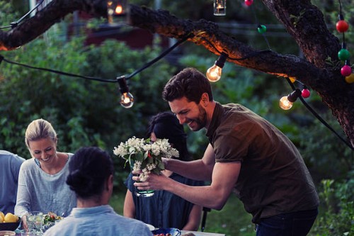 happy man holding flower vase while enjoying dinner party with friends at yard - garden decoration stock pictures, royalty-free photos & images