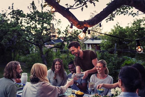 happy man serving water to friend during dinner party at yard - garden decoration stock pictures, royalty-free photos & images