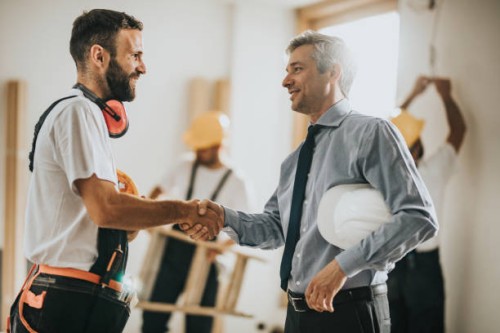 happy manual workers shaking hands with an architect at construction site. - home decoration stock pictures, royalty-free photos & images