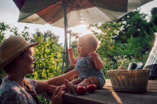 happy mother and daughter baby with harvest in garden having fun. - garden decoration photos et images de collection