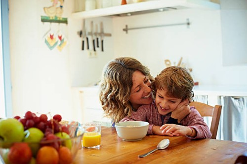 happy mother embracing son having breakfast - food stock pictures, royalty-free photos & images