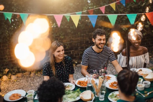 happy multi-ethnic friends enjoying dinner at table during garden party - garden decoration stock pictures, royalty-free photos & images